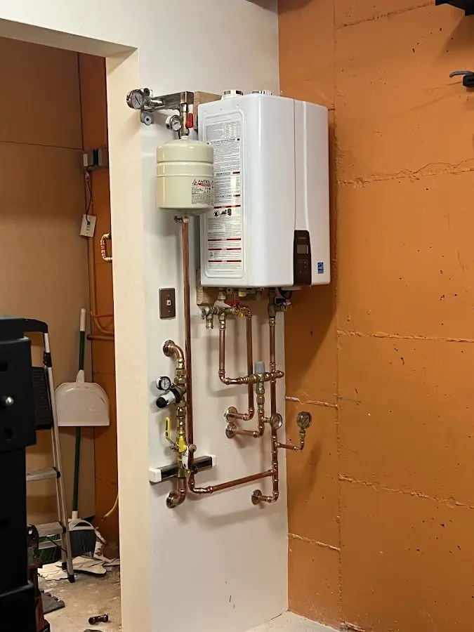 Plumbing technician inspecting water heater connections in Mechanic Falls